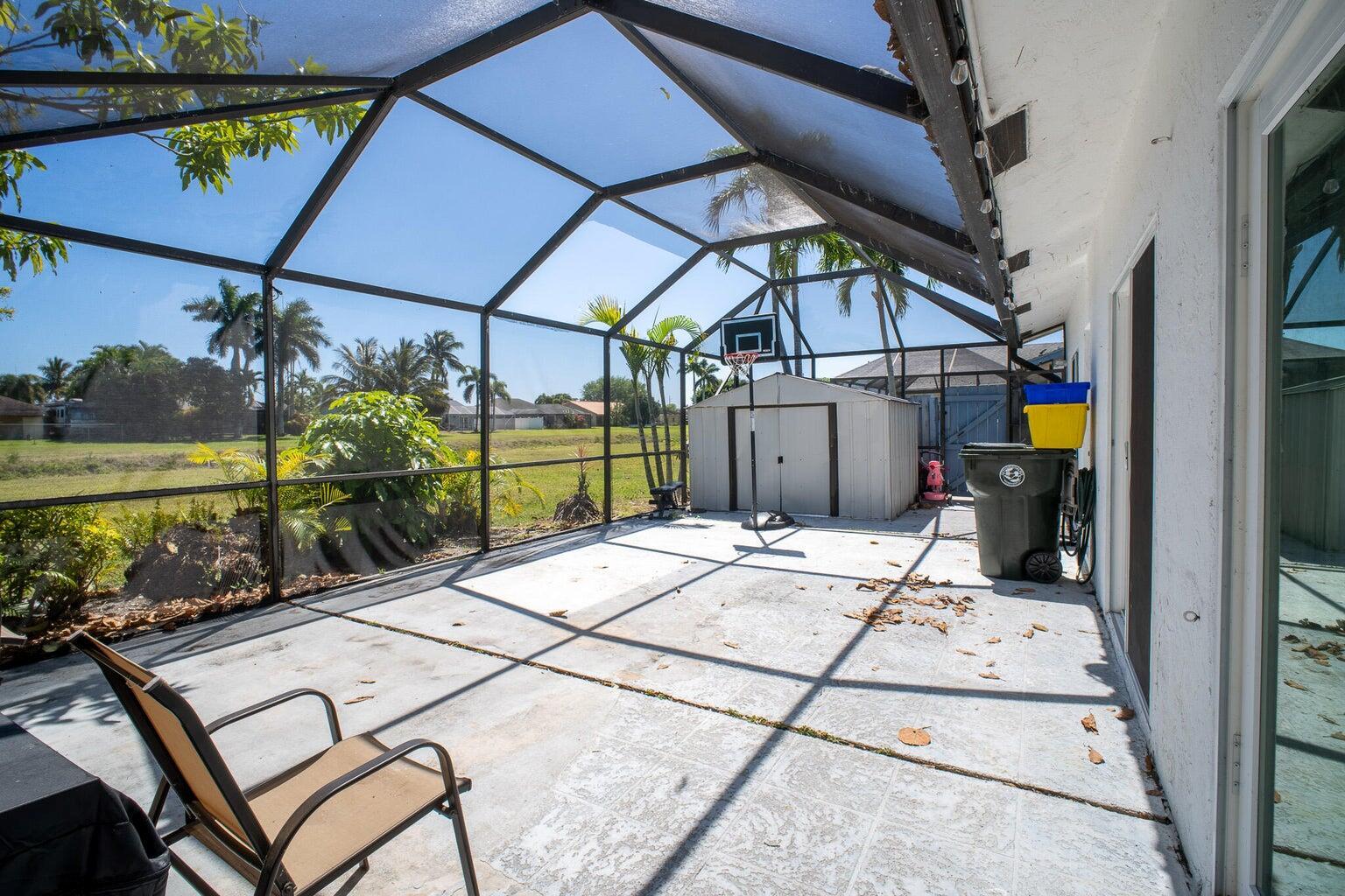 A screened-in patio features a concrete floor, a basketball hoop, and a storage shed — 1103 Timberlane Circle, FL 33463, FL