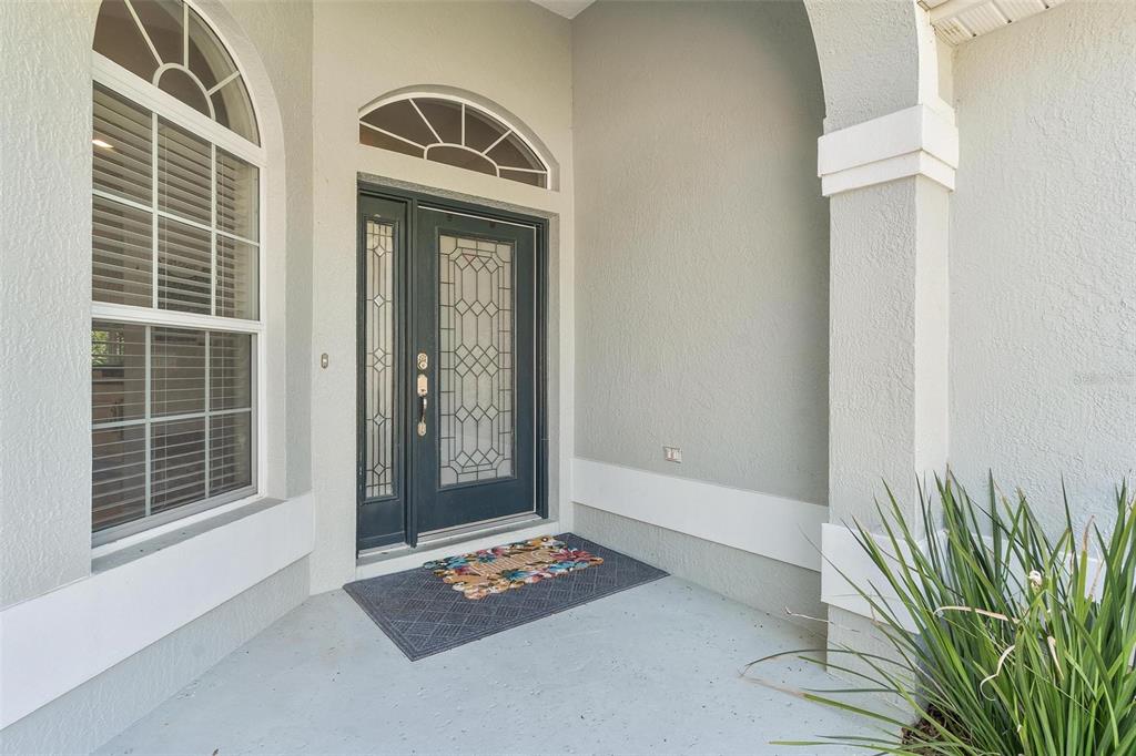 A front entryway features a dark-framed glass door, a side light, and a arched window — 1027 URICO GOLF ROAD, LADY LAKE, FL