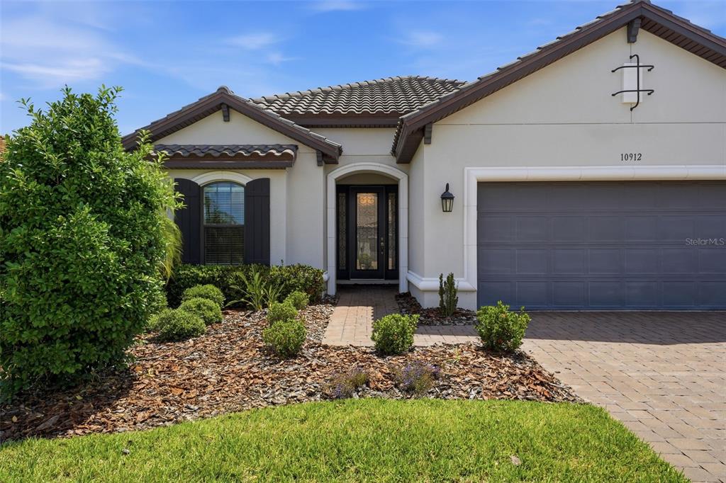 A single-story house with a gray garage, arched entryway, and landscaped front yard — 10912 SEASONS WAY, PALMETTO, FL