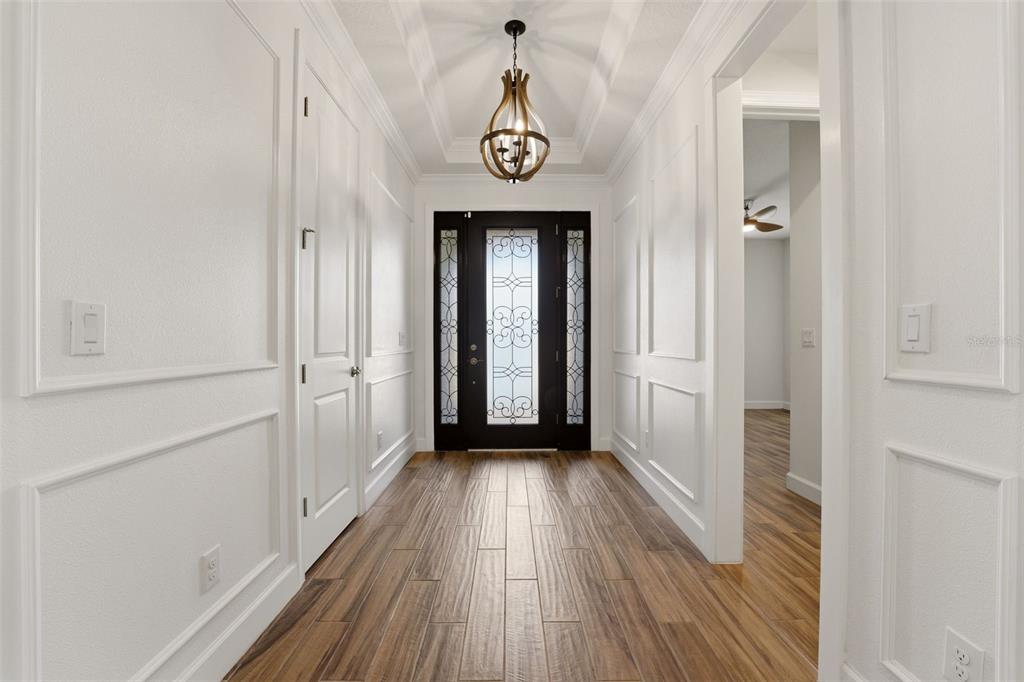 A bright entryway features white paneled walls, wood-look tile flooring, and a decorative pendant light — 10912 SEASONS WAY, PALMETTO, FL
