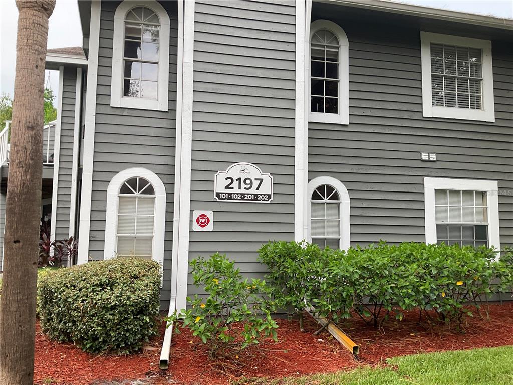 The exterior of a two-story gray building features arched windows and a unit number sign — 2197 FOX CHASE BOULEVARD UNIT 101, PALM HARBOR, FL