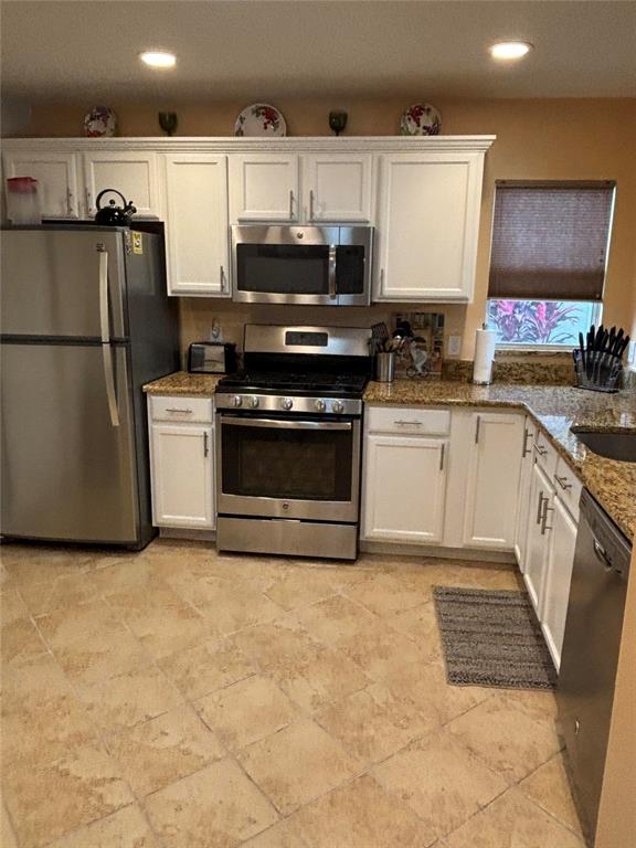 A kitchen with white cabinets, stainless steel appliances, and tan tile flooring — 1069 BURNETTOWN PLACE, THE VILLAGES, FL