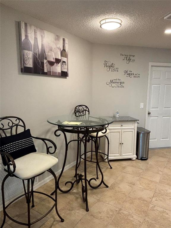 A small dining area features a glass-topped bistro table, two metal barstools, and wall art — 1069 BURNETTOWN PLACE, THE VILLAGES, FL