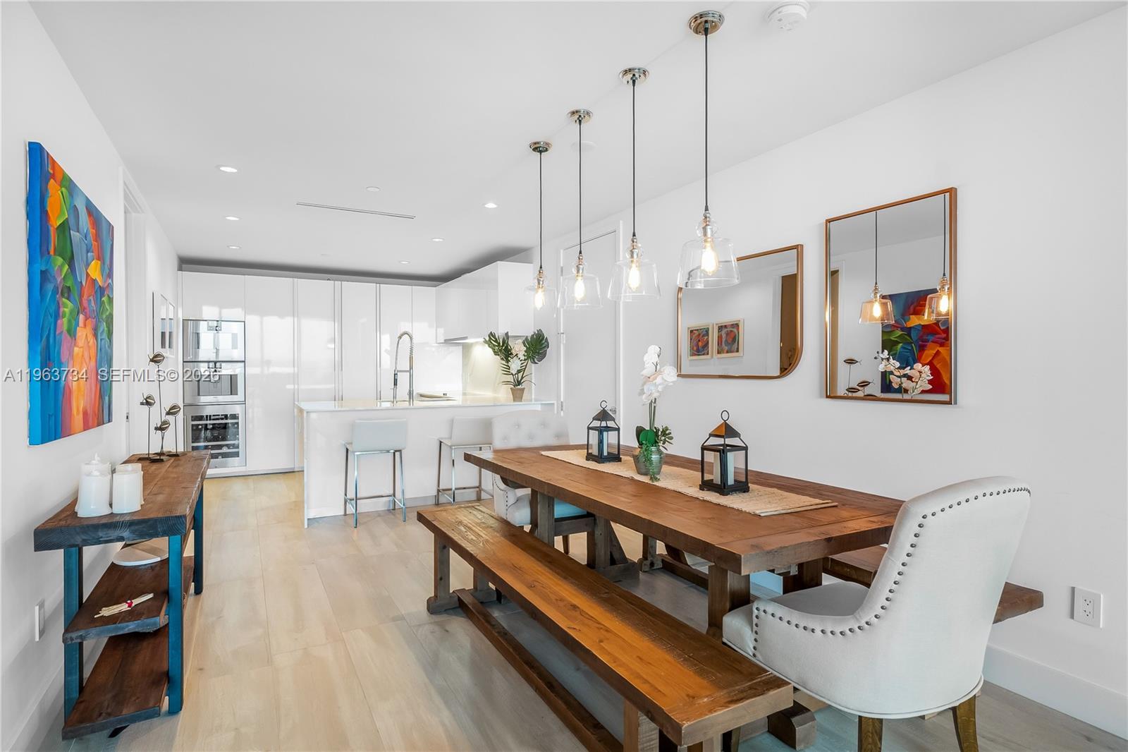 A dining area with a wooden table and bench sits adjacent to a modern kitchen — 10201 Collins Ave # 1205, Bal Harbour FL 33154, BAL HARBOUR, FL