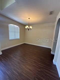 An empty dining room features dark wood-look flooring, beige walls, and a hanging chandelier — 5088 ASHWOOD DRIVE, LAKELAND, FL