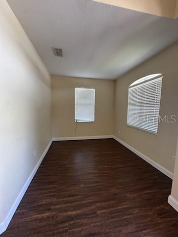 An empty room with beige walls, dark wood-look flooring, and two windows with white blinds — 5088 ASHWOOD DRIVE, LAKELAND, FL