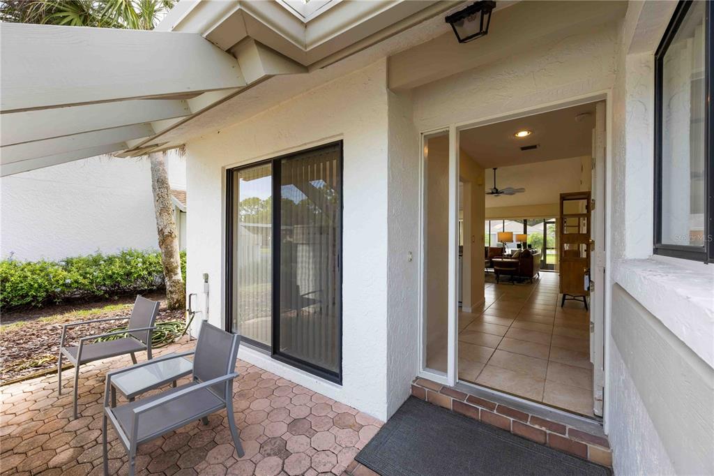 A patio with a brick floor and two chairs leads into a tiled home interior — 5370 MYRTLE WOOD ROAD UNIT 56, SARASOTA, FL