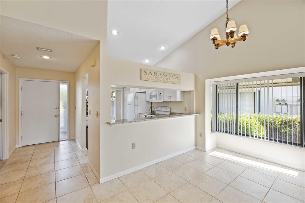 A dining area with tile floors and a breakfast bar overlooks a kitchen — 5370 MYRTLE WOOD ROAD UNIT 56, SARASOTA, FL