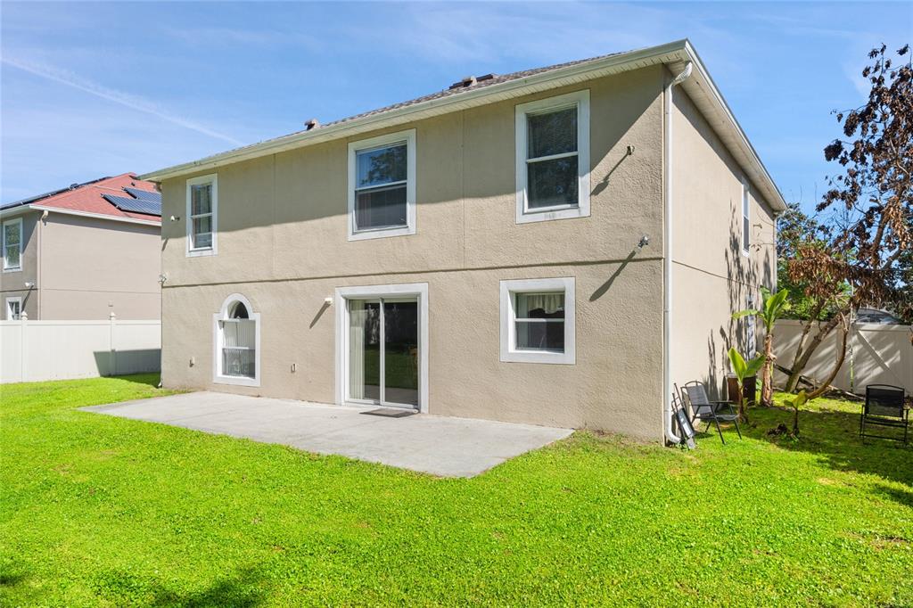 The exterior of a two-story stucco house features a concrete patio and a grassy backyard — 2554 PALMETTO RIDGE CIRCLE, APOPKA, FL