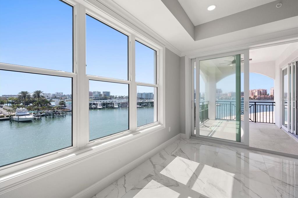 A sunroom with marble floors, large windows, and a sliding door opening to a balcony — 211 DOLPHIN POINT UNIT 303, CLEARWATER, FL