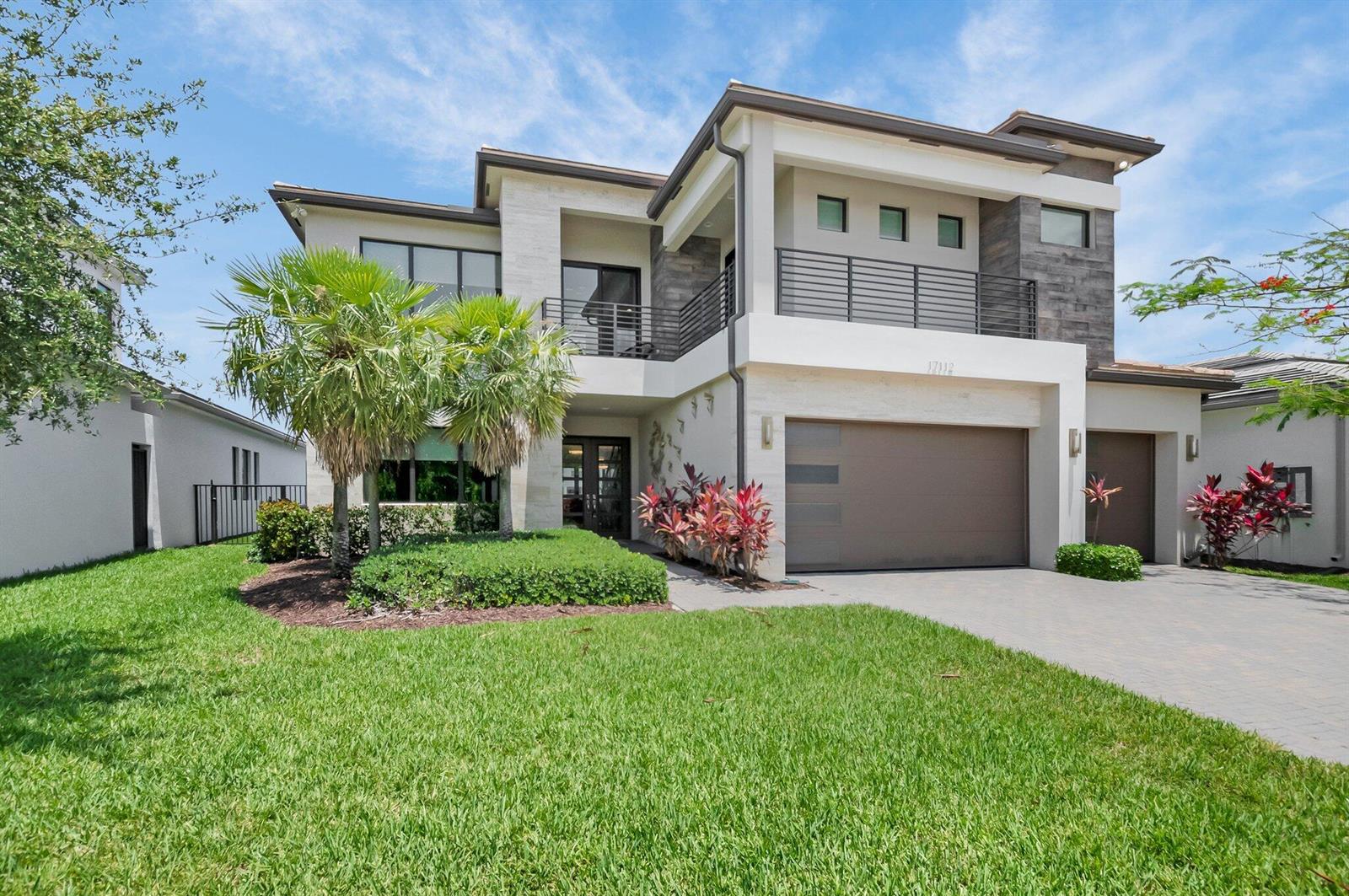 A modern two-story house features a stone facade, a balcony, and a paved driveway — 17112 Aquavera Way, Boca Raton FL 33496, BOCA RATON, FL