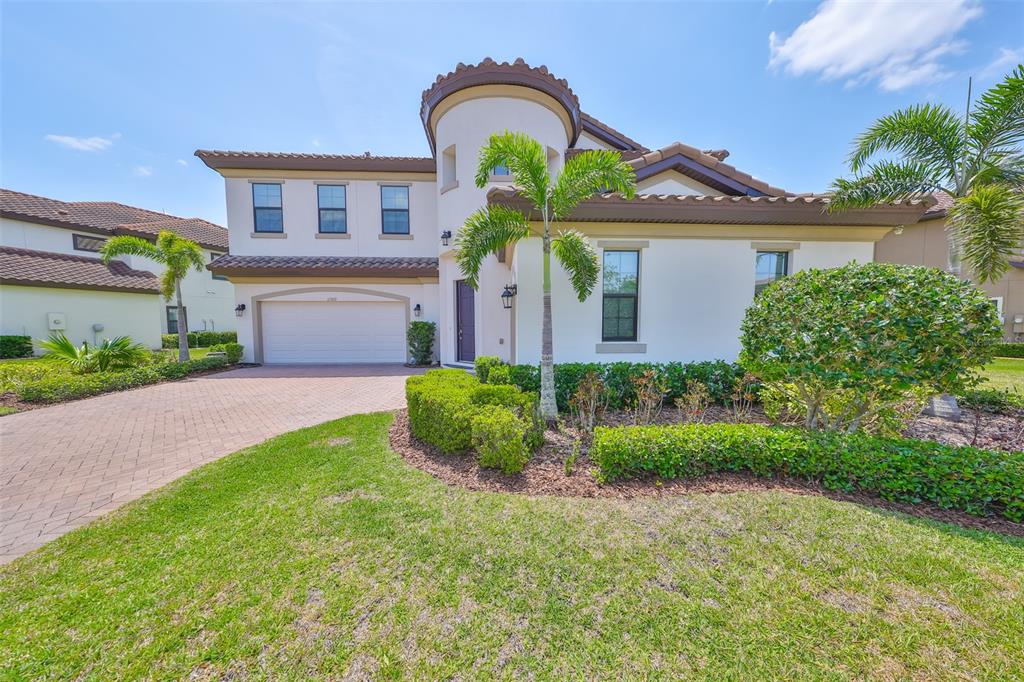 A two-story house with a white stucco exterior, a tile roof, and a paved driveway — 11909 CLIMBING FERN AVENUE, RIVERVIEW, FL