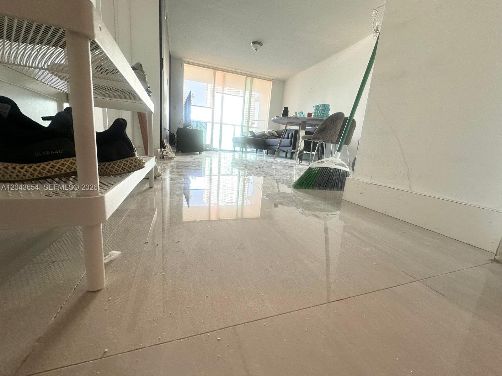 A low-angle view of a living room with light-colored tile flooring and a balcony view — 31 SE 5th # 1203, Miami FL 33131, MIAMI, FL