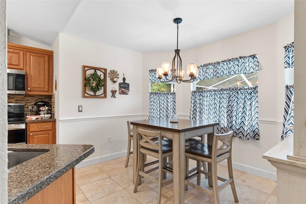 A kitchen and dining area features wood cabinets, tile flooring, and a square dining table — 2010 DEERBROOK DRIVE, LAKELAND, FL