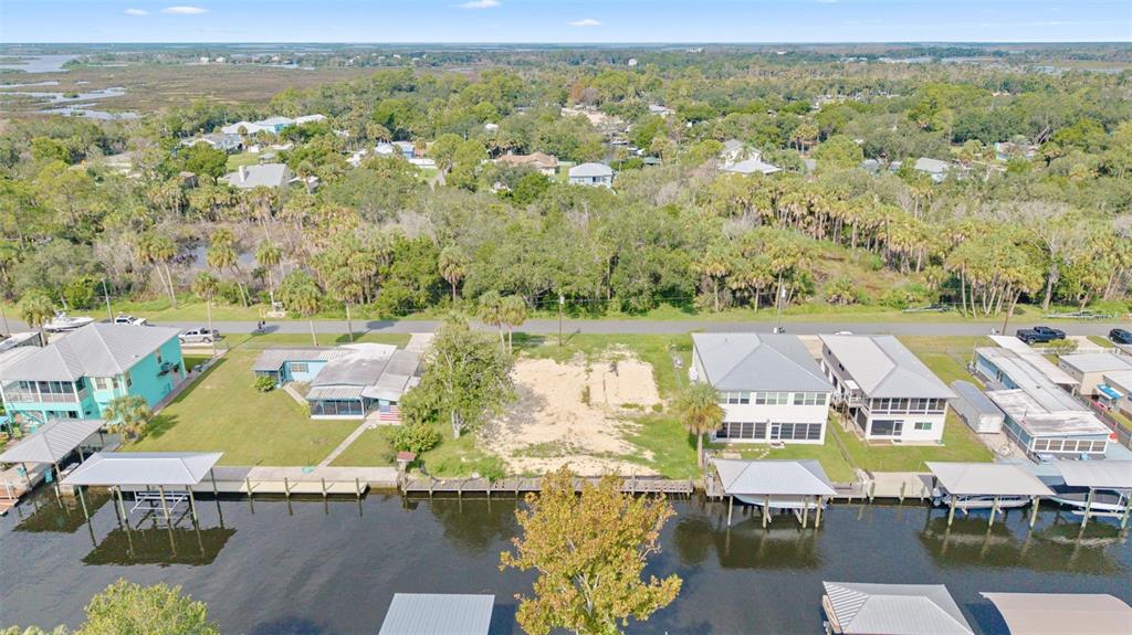 An aerial view shows a vacant waterfront lot situated between two houses with private docks — 2607 N SENECA POINT, CRYSTAL RIVER, FL