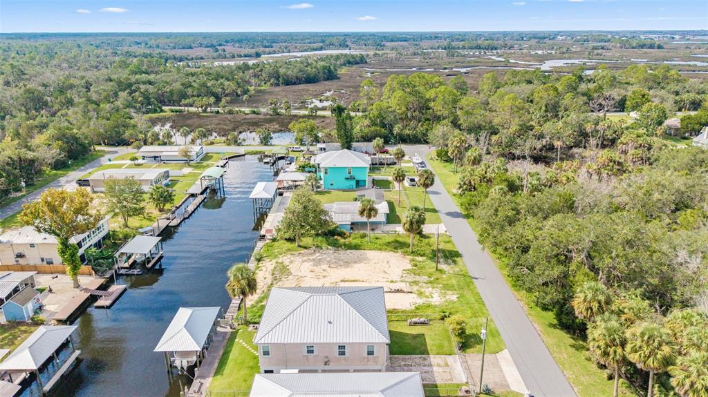 An aerial view shows waterfront homes along a canal with boat docks and surrounding vegetation — 2607 N SENECA POINT, CRYSTAL RIVER, FL