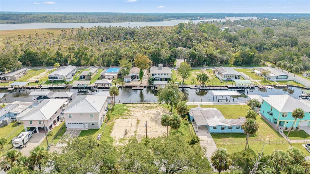 An aerial view shows a vacant waterfront lot situated between two houses along a canal — 2607 N SENECA POINT, CRYSTAL RIVER, FL