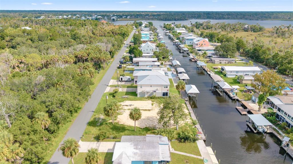 An aerial view shows a canal-side neighborhood with houses, a vacant lot, and vegetation — 2607 N SENECA POINT, CRYSTAL RIVER, FL