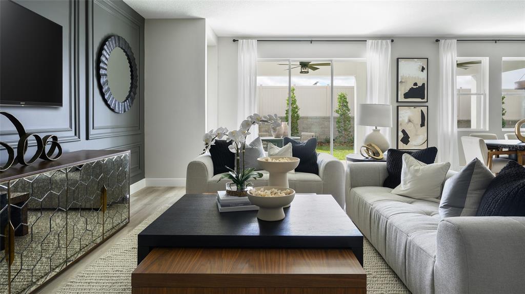 A modern living room features a dark accent wall, mirrored console, and two light-colored sofas — 33572 HAMMOCK BEACH WAY, DADE CITY, FL