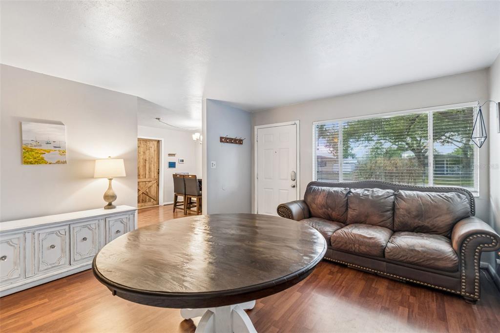 A living room features a round wooden table, a leather sofa, and a white console — 4437 W BAY AVENUE, TAMPA, FL