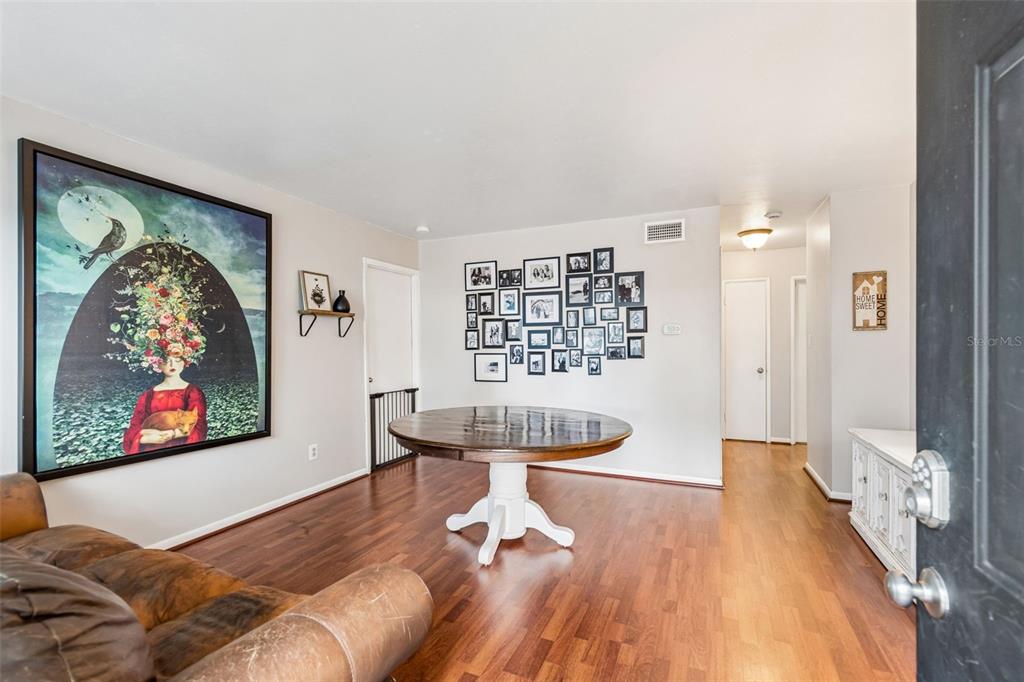 A dining area features a round wooden table, a gallery wall, and hardwood flooring — 4437 W BAY AVENUE, TAMPA, FL