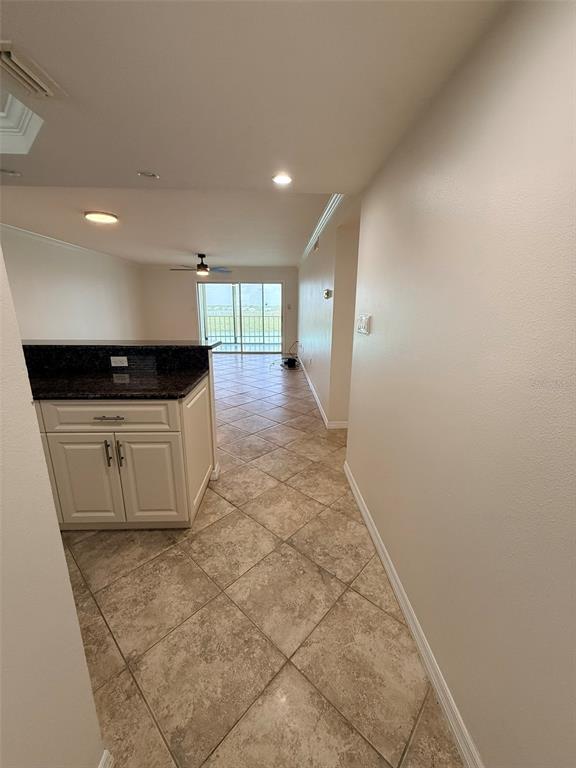 A view from a hallway looking into a kitchen with dark countertops and tiled floors — 9393 MIDNIGHT PASS ROAD UNIT 806, SARASOTA, FL