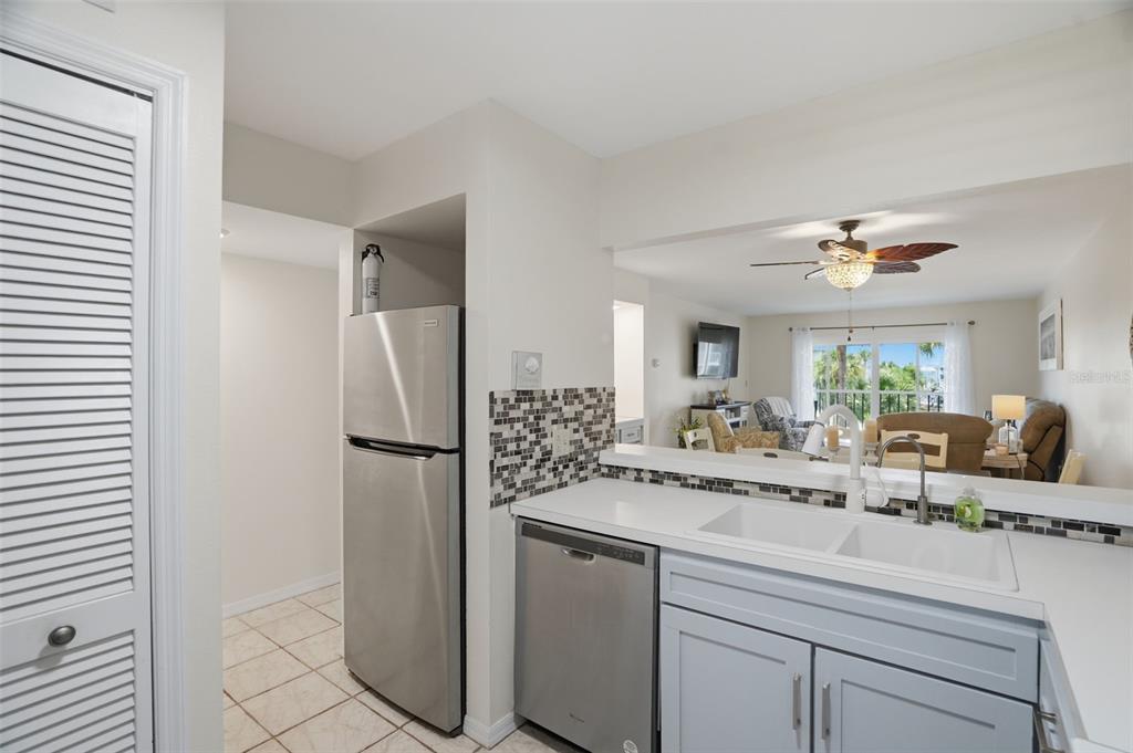 A kitchen with stainless steel appliances, a white sink, and a view into the living room — 5557 SEA FOREST DRIVE UNIT 215, NEW PORT RICHEY, FL