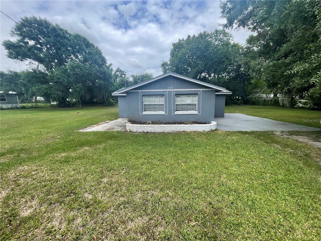 A gray, single-story house with two windows and a white brick planter in the front yard — 1225 NEMETH STREET, AUBURNDALE, FL