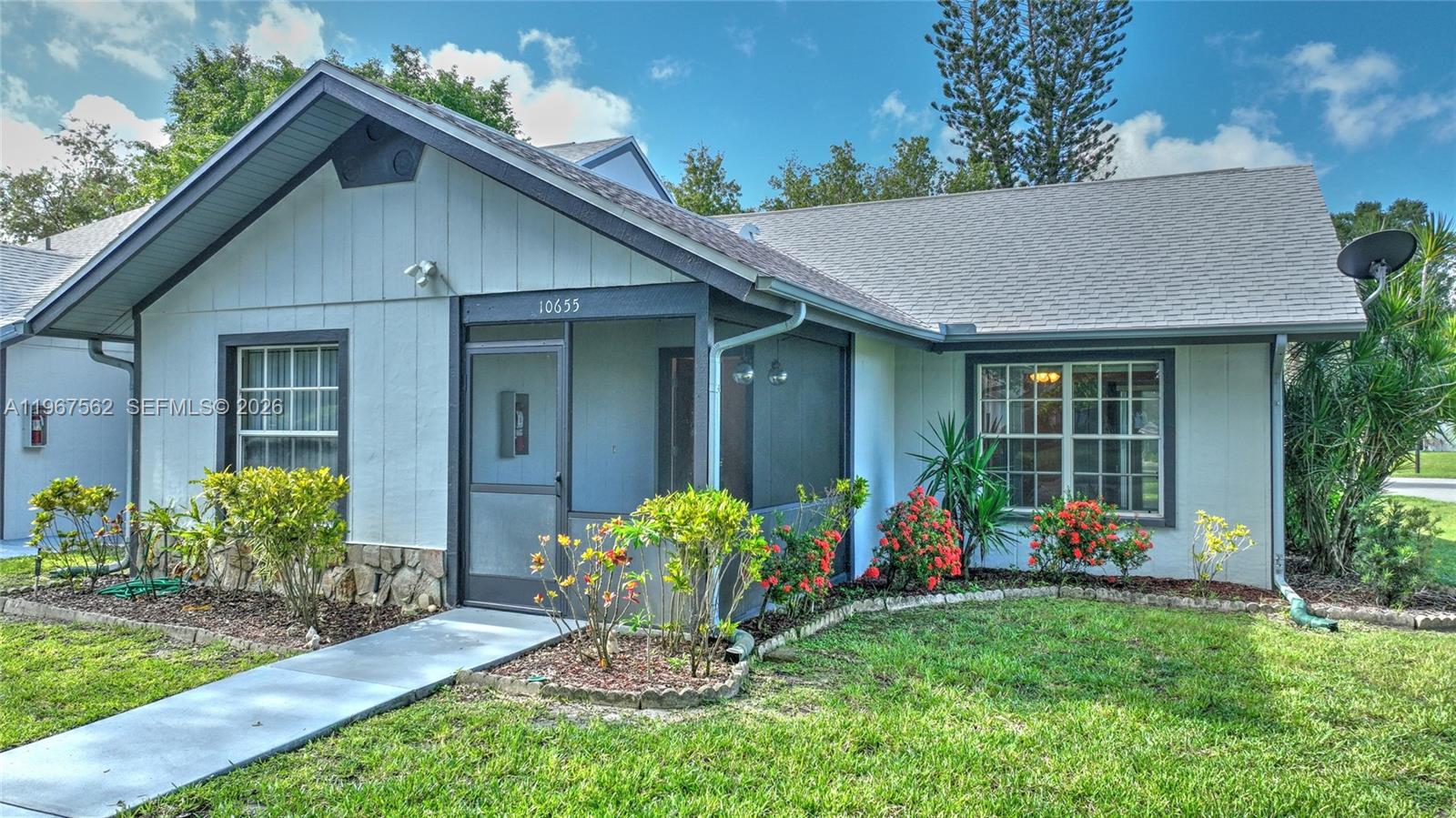 A single-story house with a screened front porch, light-colored siding, and a landscaped yard — 10655 Vanceboro Ct., Lehigh Acres FL 33936, LEHIGH ACRES, FL