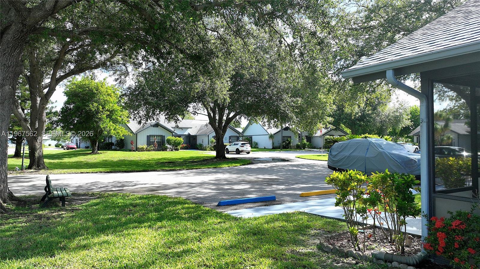 A view of a residential parking area with trees, a covered car, and houses — 10655 Vanceboro Ct., Lehigh Acres FL 33936, LEHIGH ACRES, FL