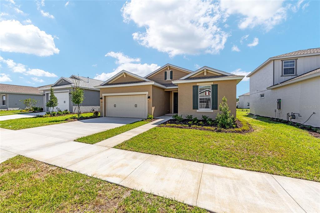 A tan single-story suburban house with a two-car garage and a concrete driveway — 5705 SW 71ST AVENUE, OCALA, FL