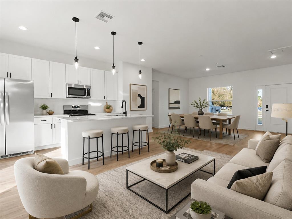 This open-concept living area features a modern kitchen with white cabinetry and a dining space — 3826 W LON LANE, DUNNELLON, FL