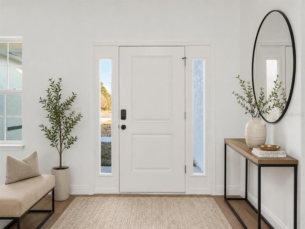 A bright entryway features a white front door with sidelights, a console table, and mirror — 3826 W LON LANE, DUNNELLON, FL