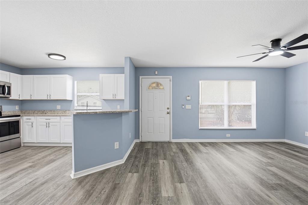A kitchen with white cabinets and a living area with light blue walls and flooring — 8309 N 12TH STREET, TAMPA, FL