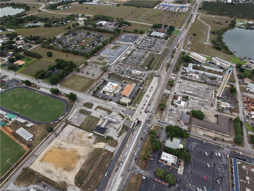 Aerial view of a commercial area with a highlighted vacant lot near a sports field — DAL HALL, LAKE PLACID, FL