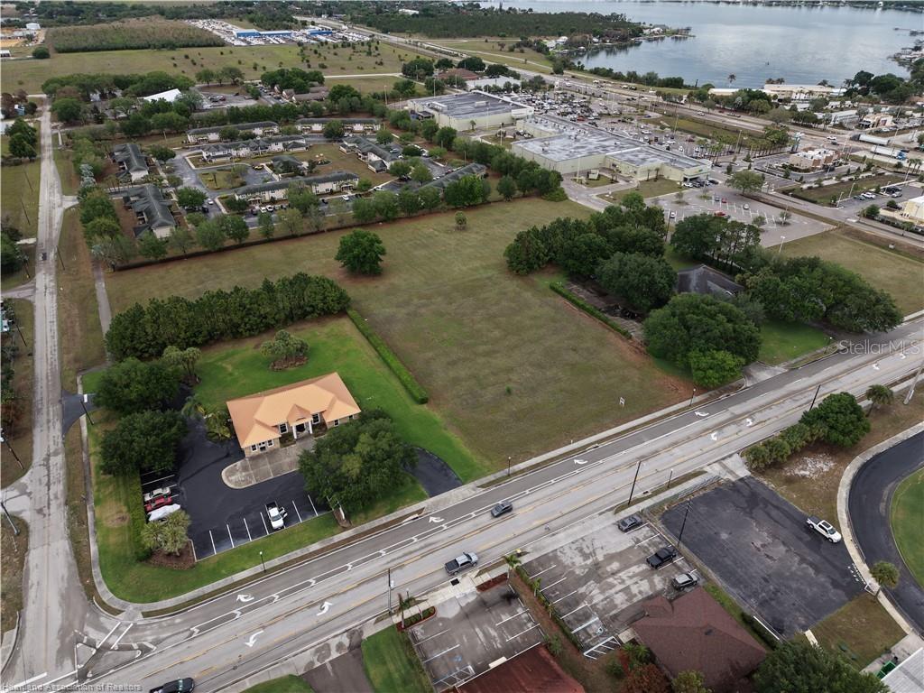 An aerial view shows a commercial building and a large vacant lot beside a road — DAL HALL, LAKE PLACID, FL