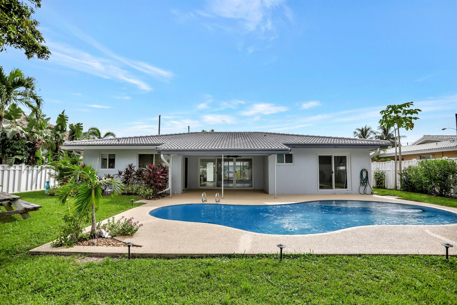 The backyard features a swimming pool, a covered patio, and a lawn with tropical landscaping — 421 SE 5 Terrace, Pompano Beach FL 33060, POMPANO BEACH, FL