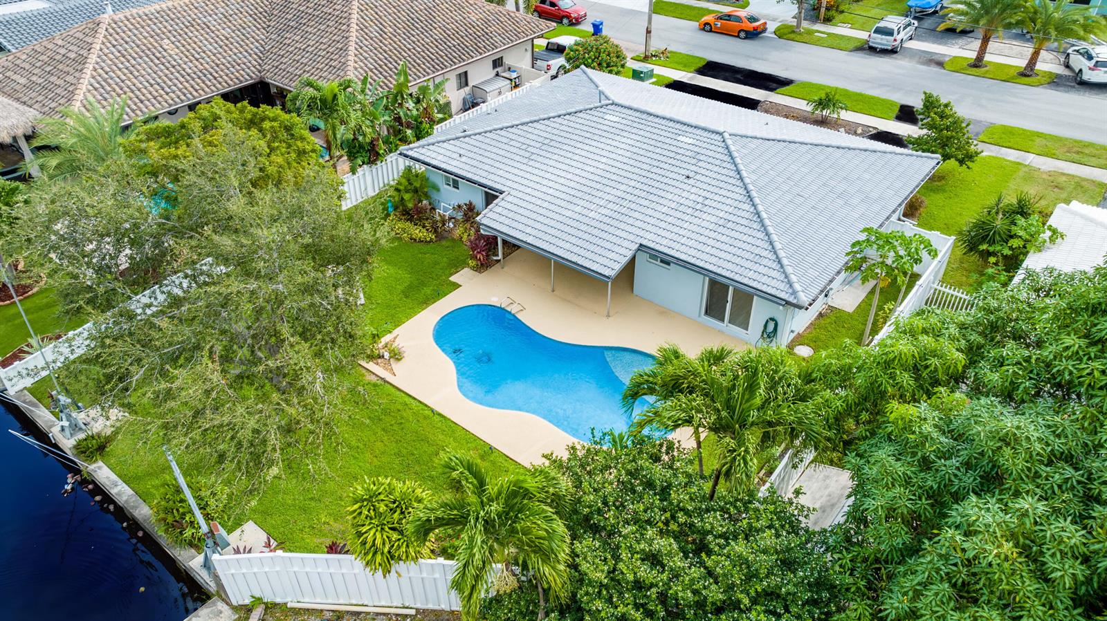 An aerial view of a house with a gray tiled roof, pool, and backyard canal — 421 SE 5 Terrace, Pompano Beach FL 33060, POMPANO BEACH, FL
