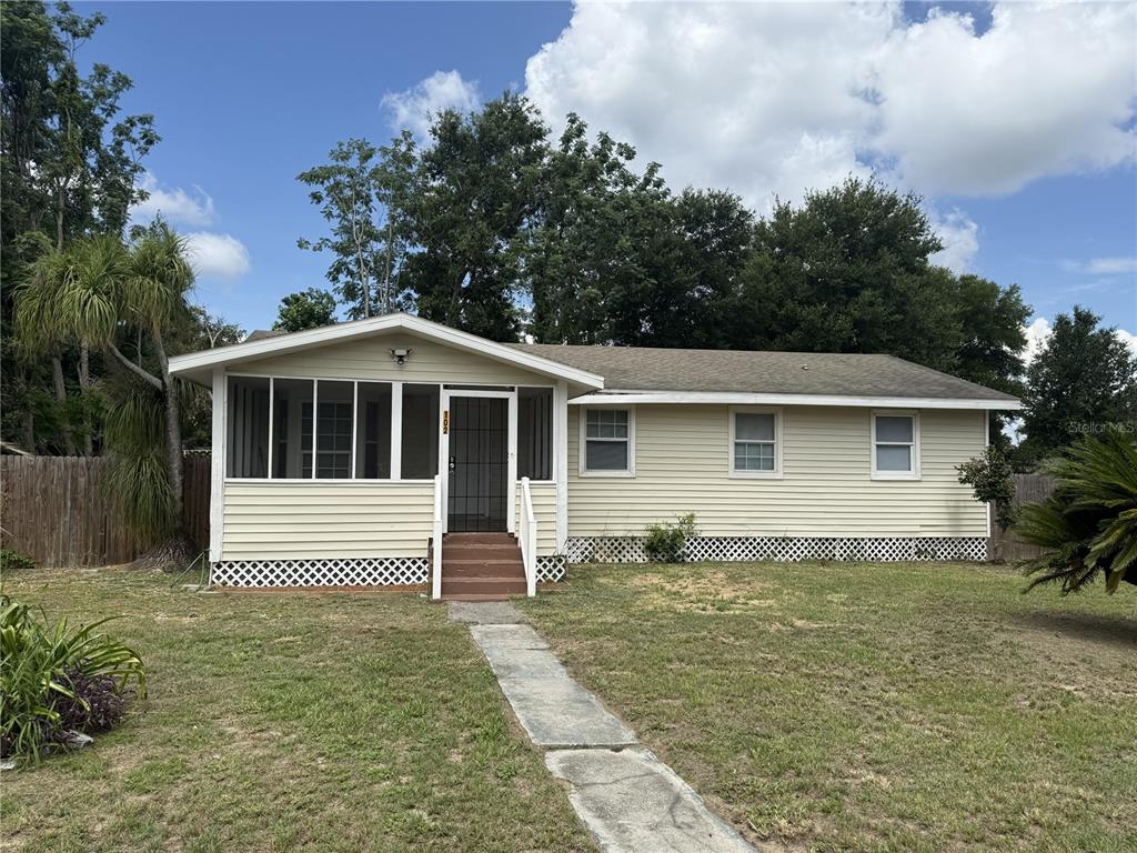 A single-story house with light yellow siding, a screened-in front porch, and a lattice foundation — 102 GROVE STREET, ORLANDO, FL