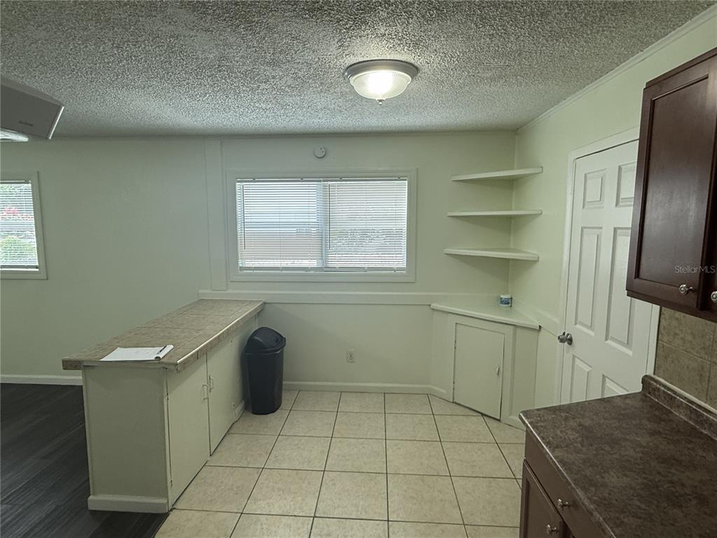 A kitchen features tile flooring, a breakfast bar, open shelving, and a white door — 102 GROVE STREET, ORLANDO, FL
