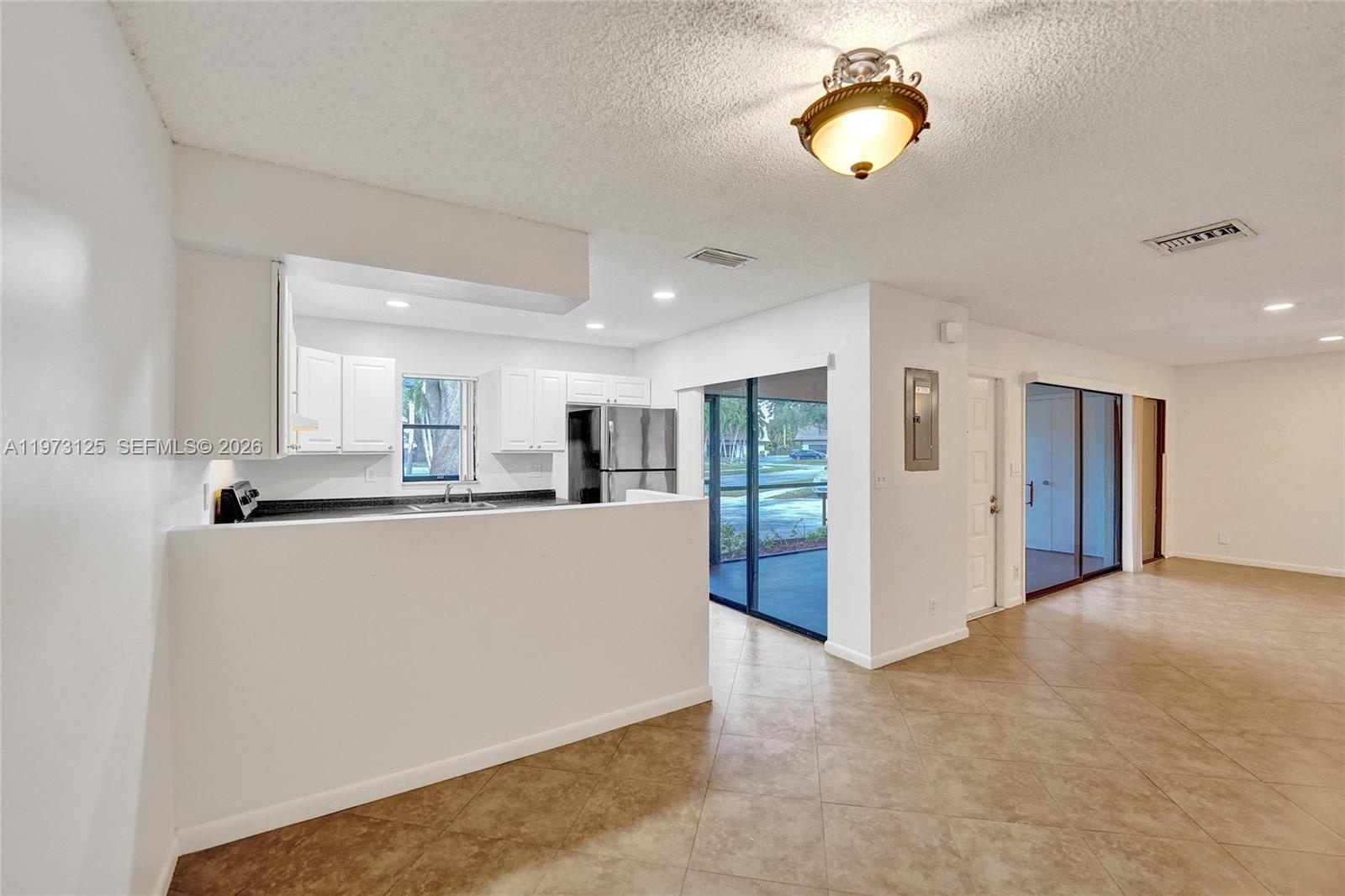 A kitchen with white cabinets and a breakfast bar opens into a living area — 9340 SW 61st Way # B, Boca Raton FL 33428, BOCA RATON, FL