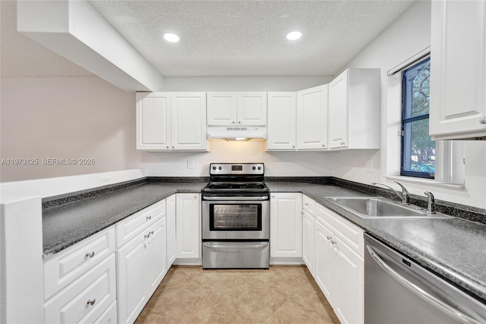 A kitchen features white cabinets, dark countertops, stainless steel appliances, and tile flooring — 9340 SW 61st Way # B, Boca Raton FL 33428, BOCA RATON, FL