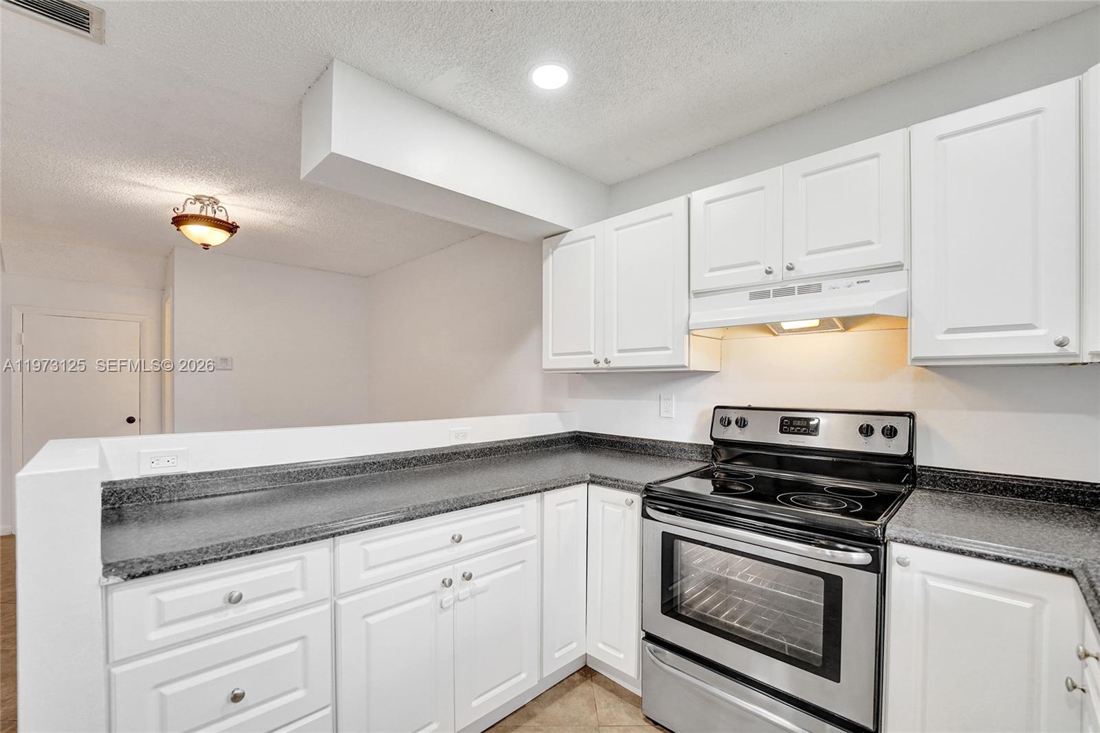 A kitchen features white cabinets, dark granite countertops, and stainless steel appliances — 9340 SW 61st Way # B, Boca Raton FL 33428, BOCA RATON, FL