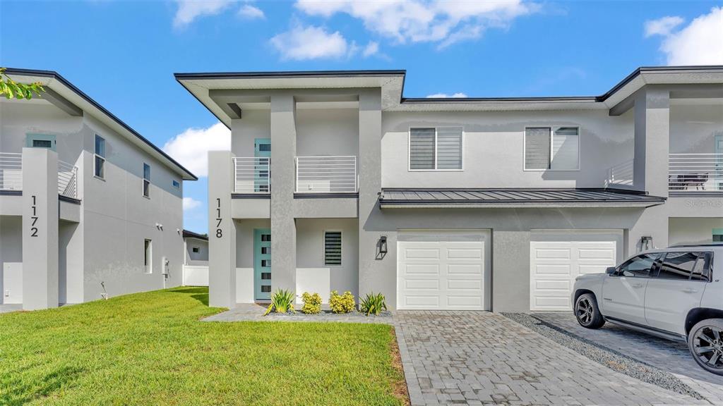 A two-story duplex with gray stucco siding, a paved driveway, and a white SUV parked — 1178 WINDJAMMER DRIVE, LAKELAND, FL