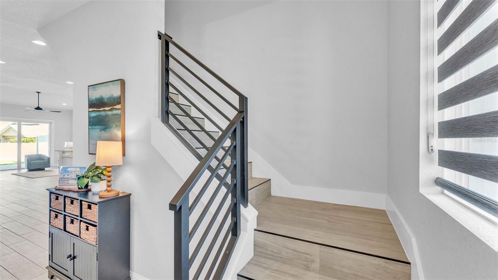 A staircase with wood-look tile steps and a black metal railing leads upward — 1178 WINDJAMMER DRIVE, LAKELAND, FL