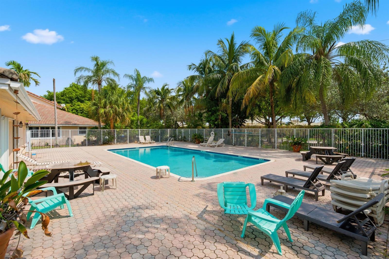 A rectangular swimming pool sits on a paved patio surrounded by palm trees and fencing — 8417 NW 40th Court, Sunrise FL 33351, SUNRISE, FL