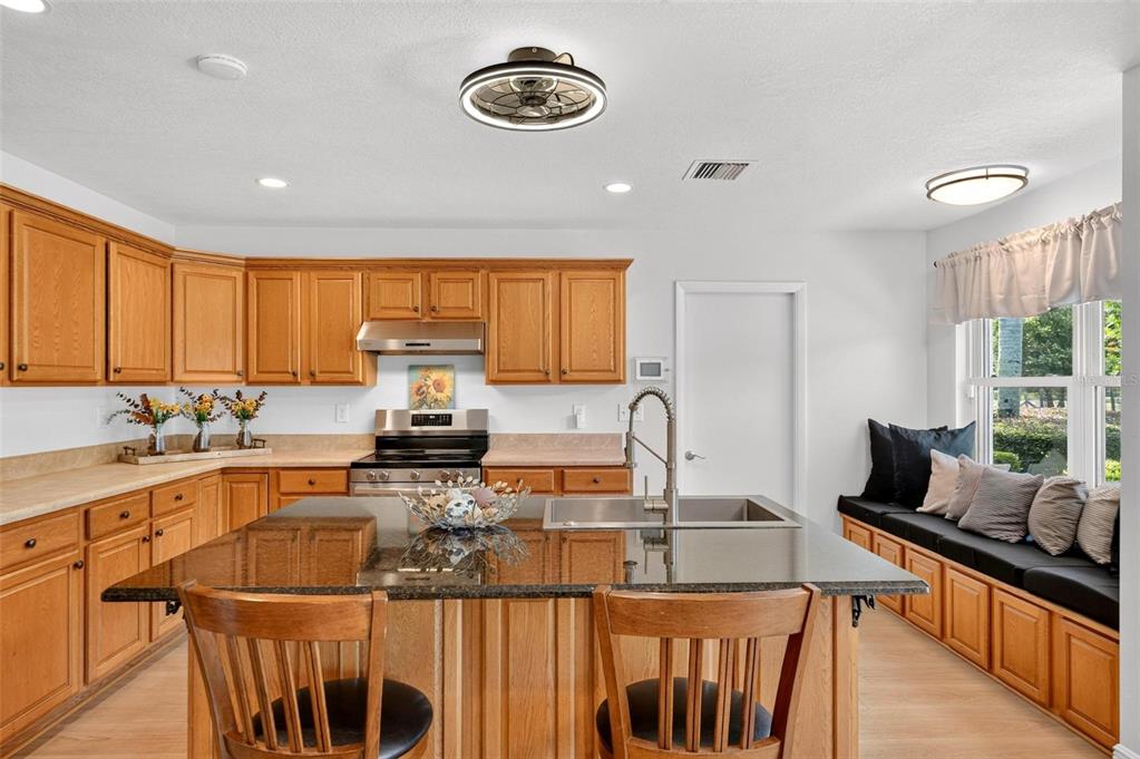 A kitchen with wood cabinets, a black granite island, and a built-in window seat — 39036 ROSE STREET, UMATILLA, FL