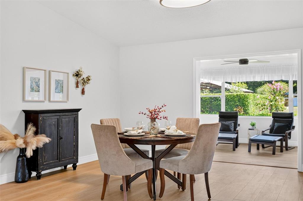 A dining area with a round table and chairs opens to a sunroom with outdoor views — 39036 ROSE STREET, UMATILLA, FL