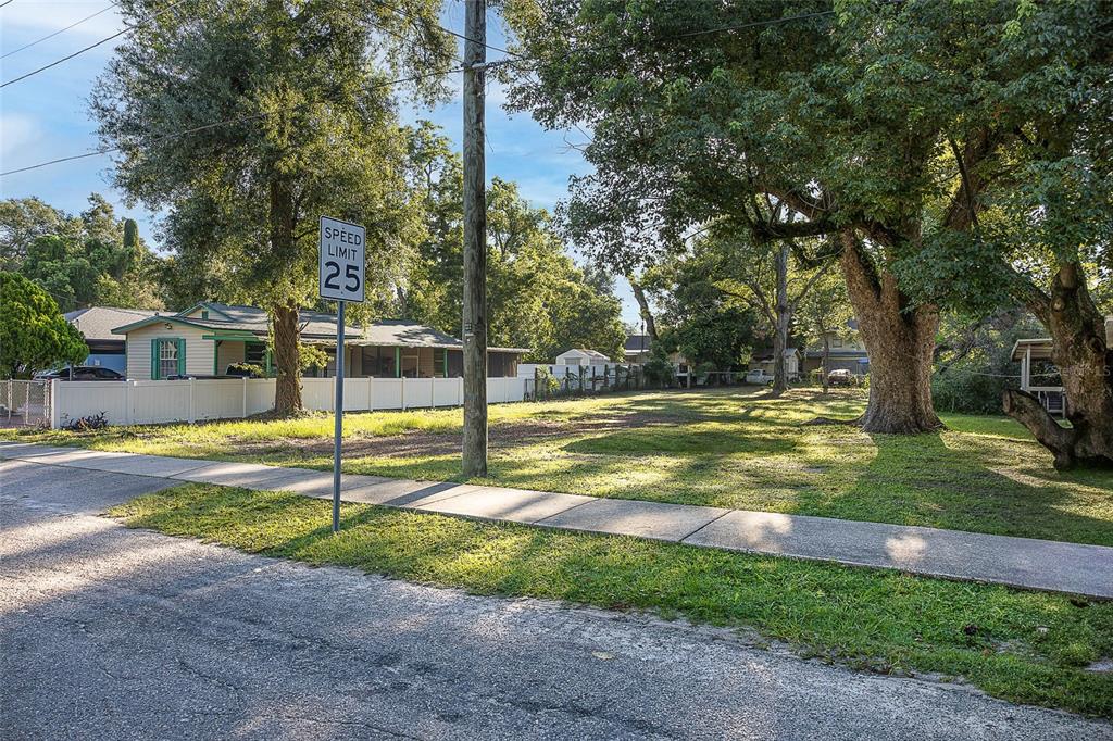 A vacant, grassy residential lot sits next to a house with a white fence — 8409 N MULBERRY STREET, TAMPA, FL