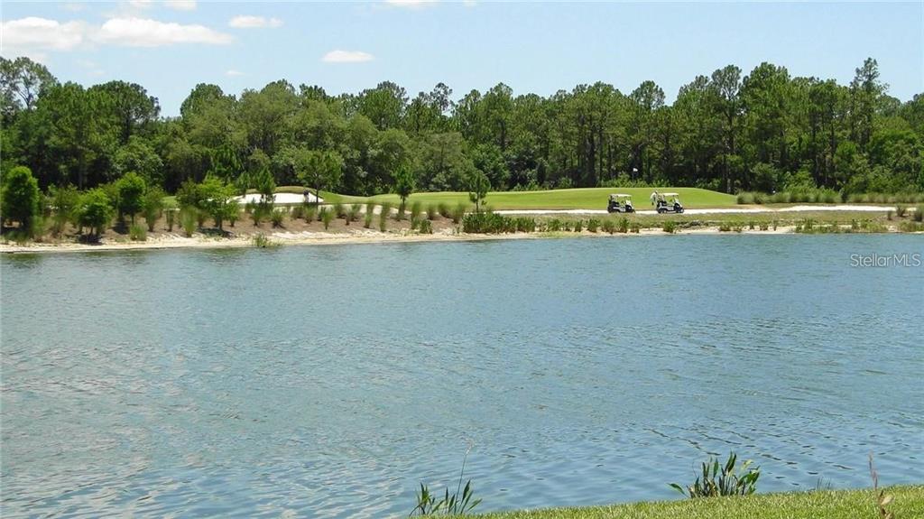 A view of a lake with a golf course and golf carts in the background — 16804 VARDON TERRACE UNIT 105, BRADENTON, FL
